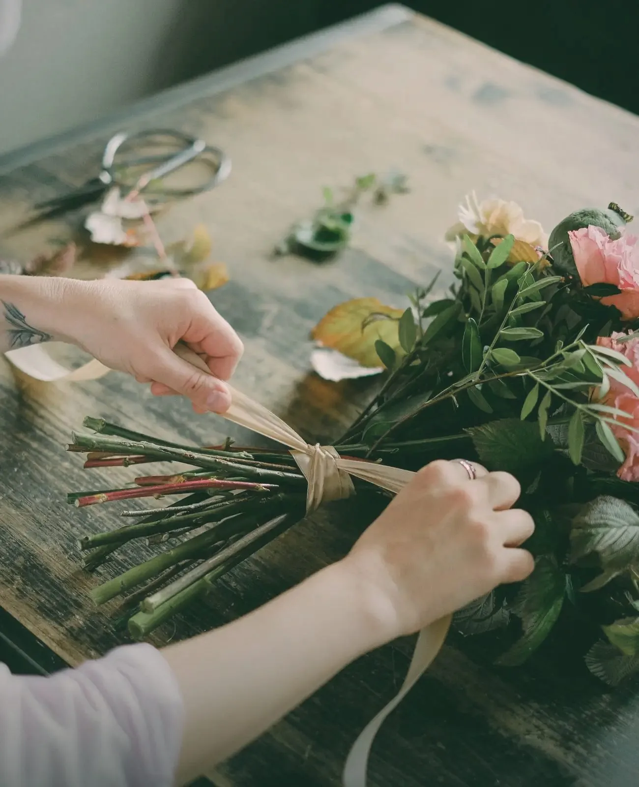 Hands tying a ribbon round the stems of a bouquet