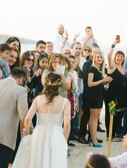 Guests cheer and take photographs as the bride walks between them.